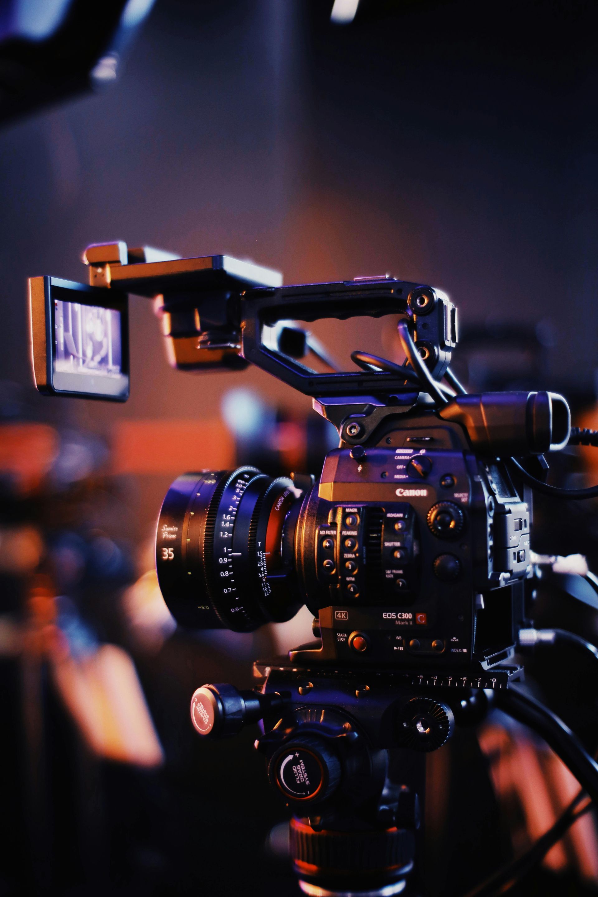 A video camera is on a tripod in a dark room