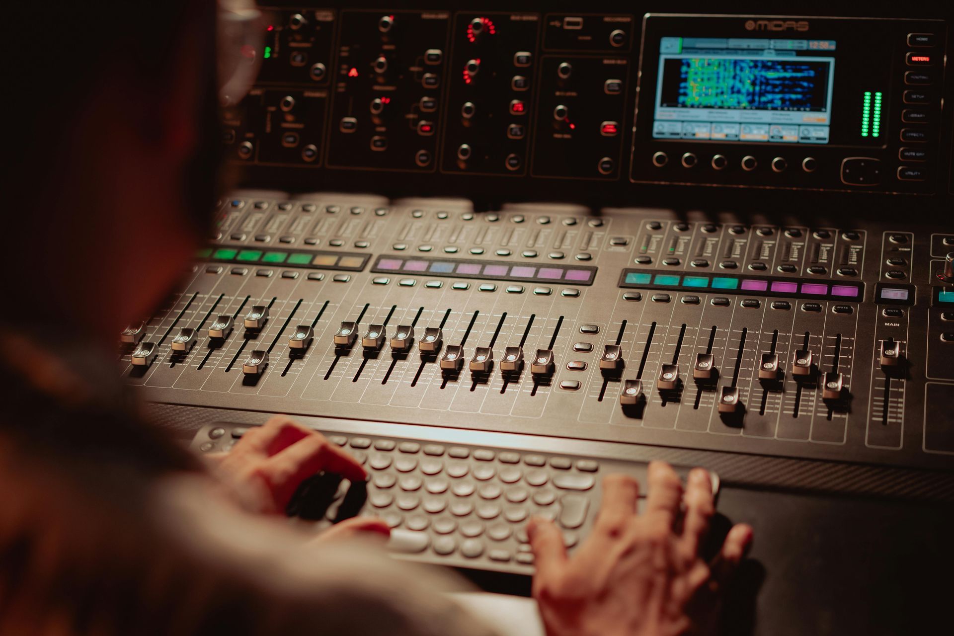 A man is typing on a keyboard in front of a mixer.