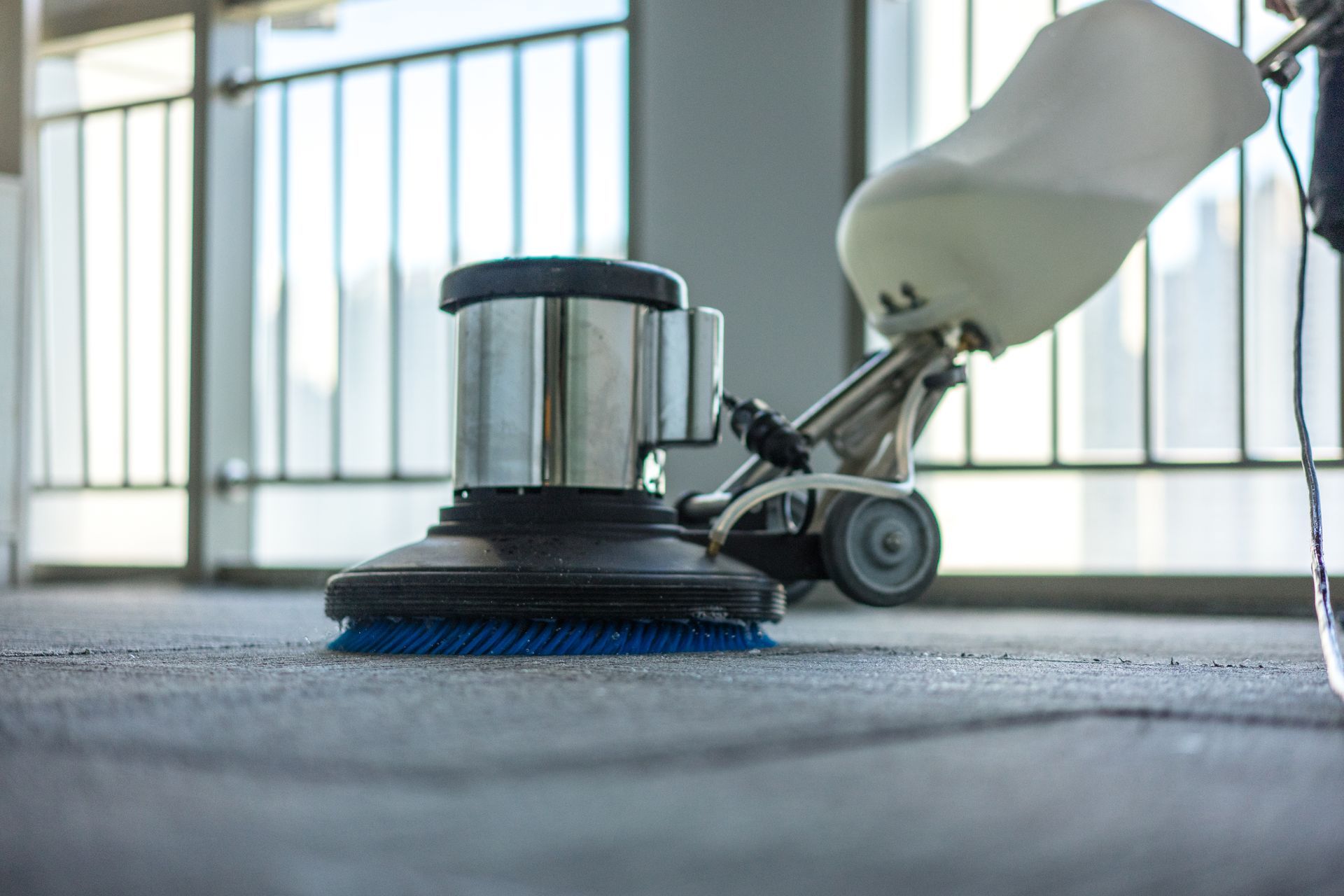 Carpet cleaning machine on a gray carpet in a bright room with large windows