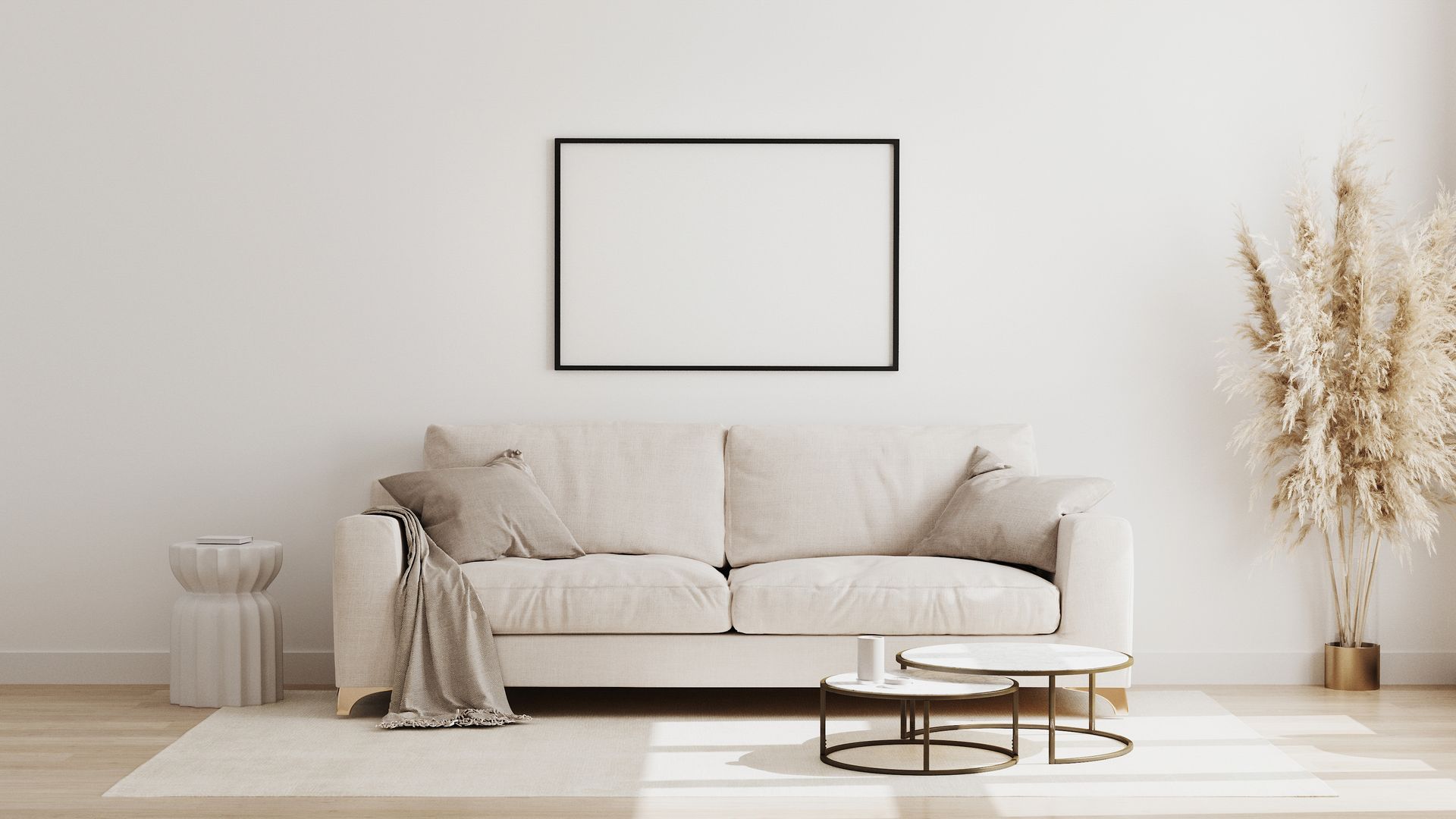 Minimalist beige living room with a sofa, blank wall art, dried grass decor, and a round coffee table.