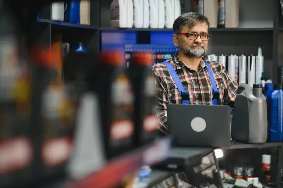 An auto-parts technician explains OEM vs. aftermarket car parts to a client off camera.