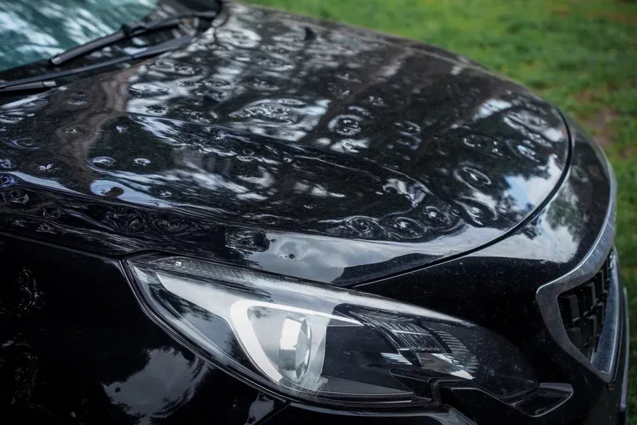 A black car’s hood damaged by hail.