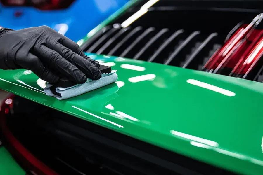 Dent Clinic expert applying a ceramic coating to a green sports car
