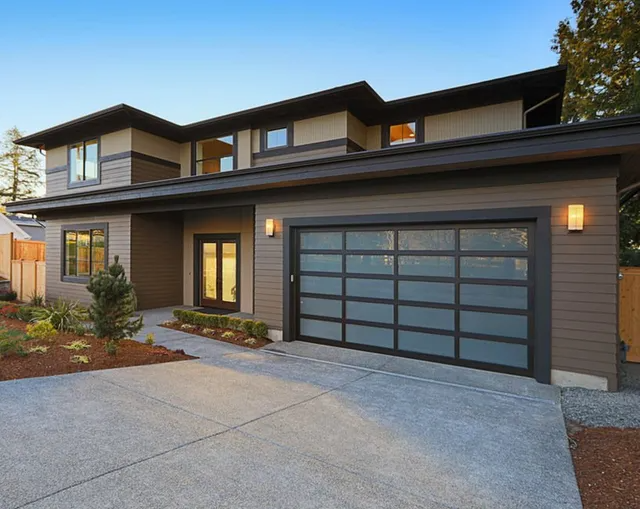Modern two-story house with gray siding and a dark garage door, viewed from the driveway at dusk — MDSR Group In Manunda, QLD