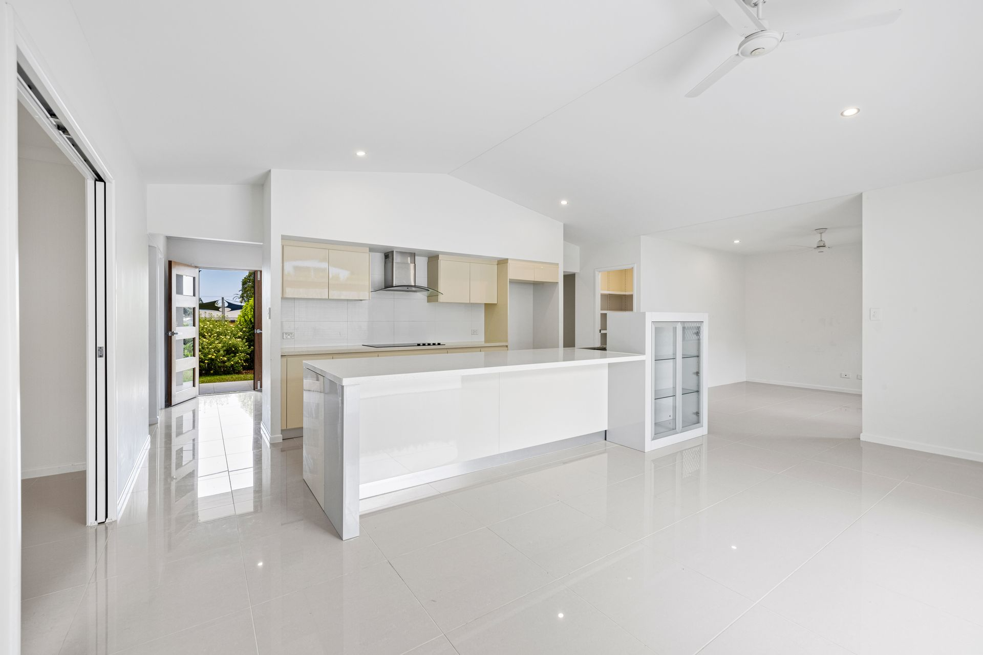 Bright white modern kitchen and open living space with glossy tile floors and minimal cabinets — MDSR Group In Manunda, QLD