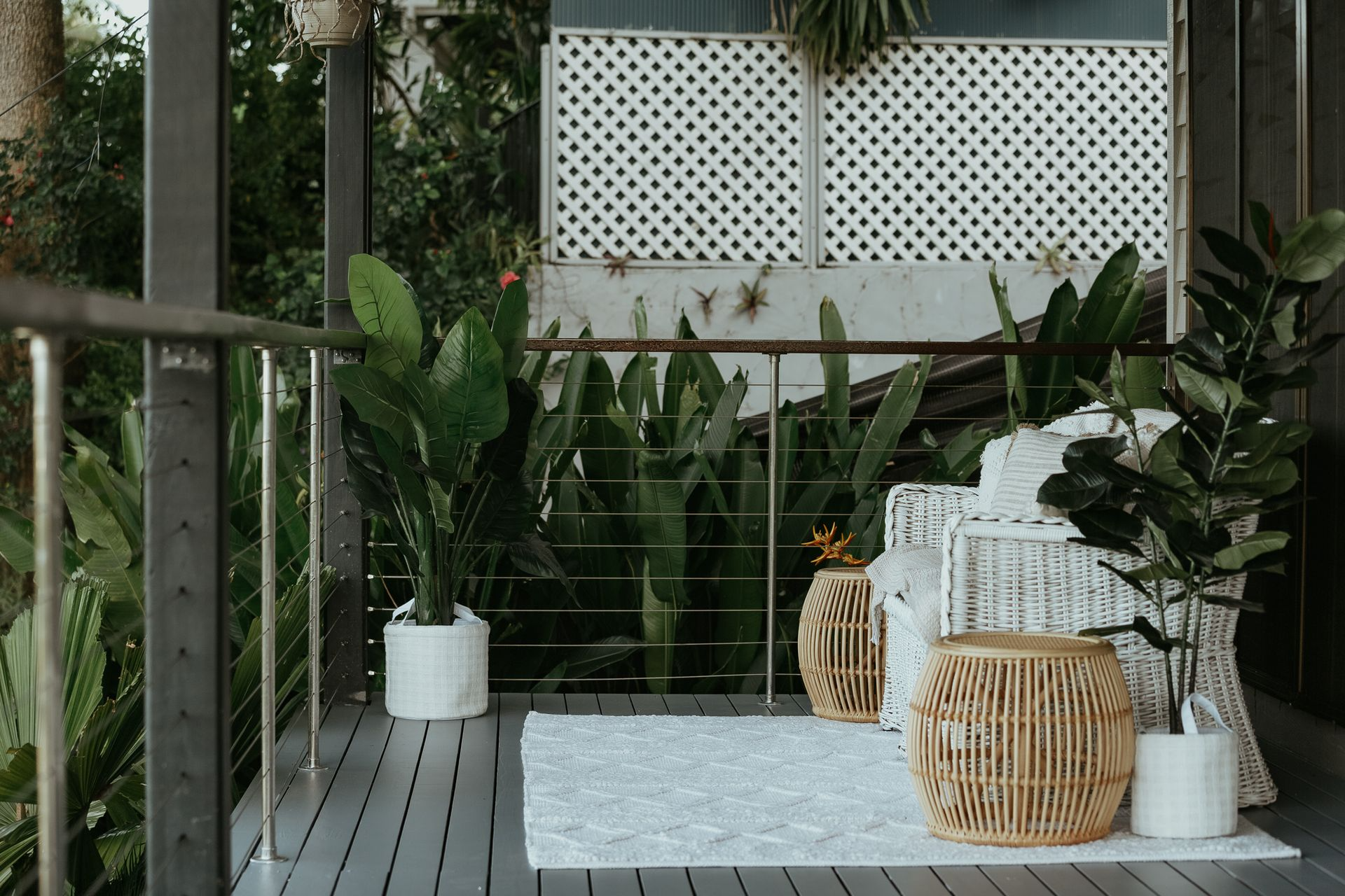 Balcony With Lush Greenery, White Accents, and Rattan Furniture — MDSR Group In Manunda, QLD