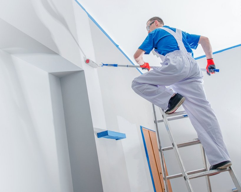 Painter Rolling White Paint on a Wall — MDSR Group In Manunda, QLD