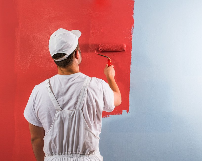 Person Painting a Wall Red With a Roller — MDSR Group In Manunda, QLD