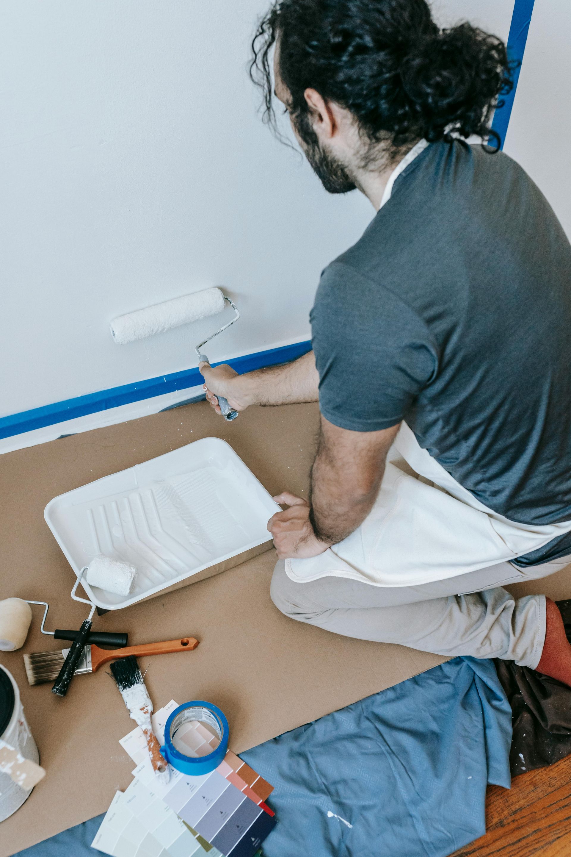 Man Paints a White Wall With a Roller — MDSR Group In Manunda, QLD