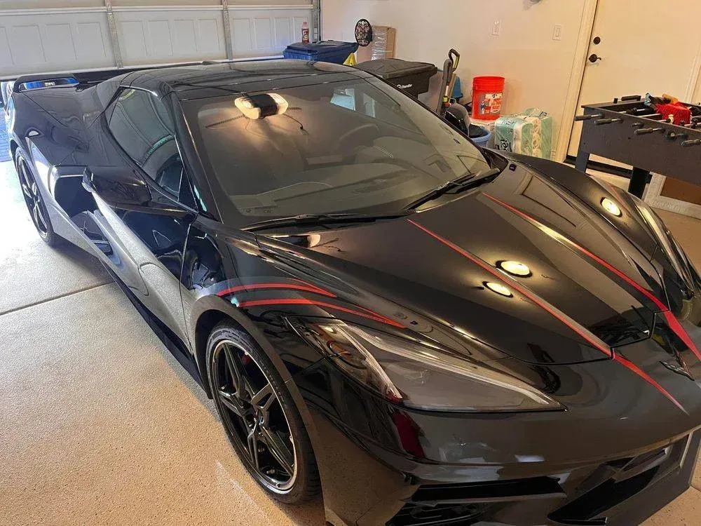 A black sports car is parked in a garage.