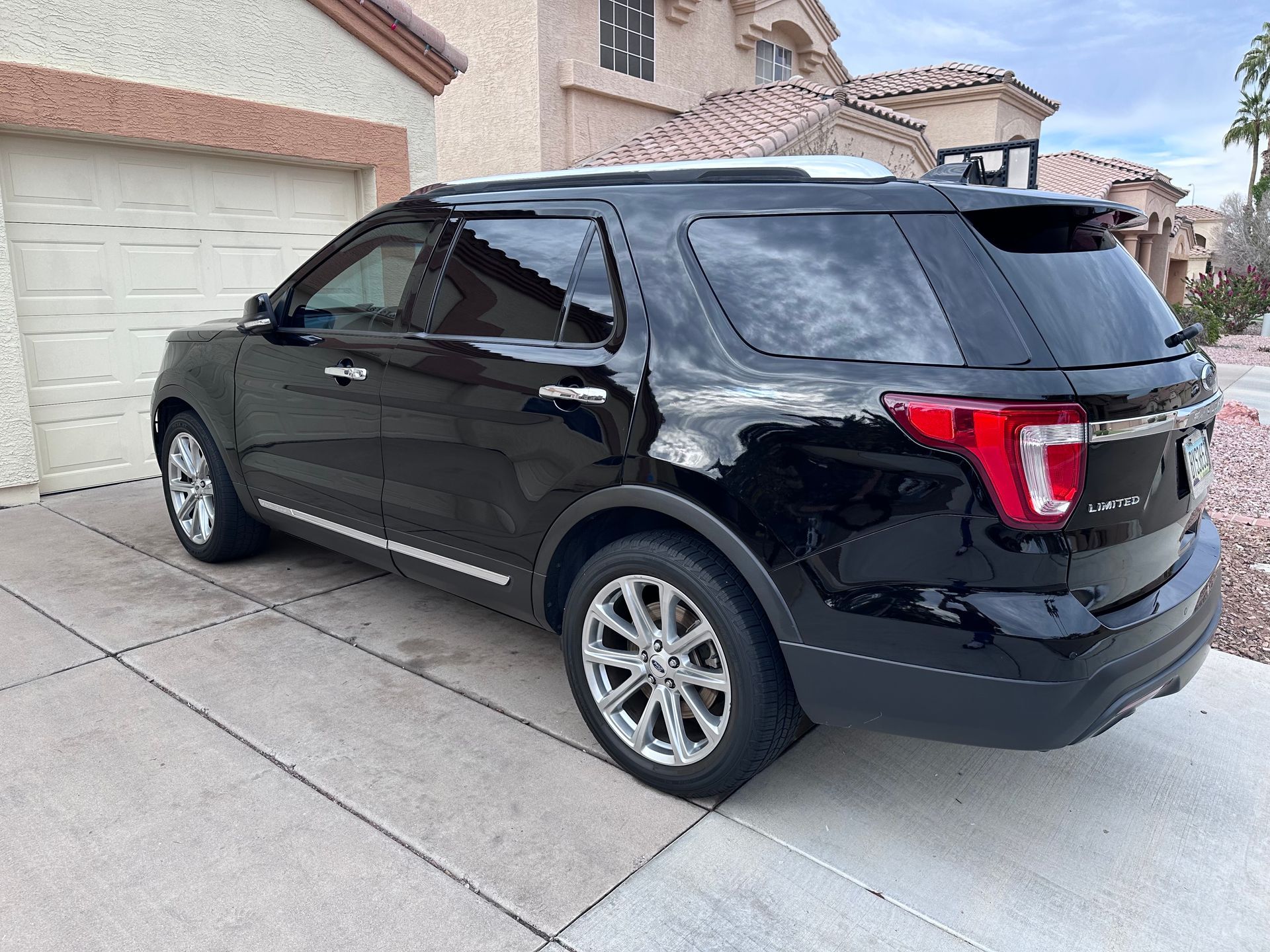 A black ford explorer is parked in front of a garage.