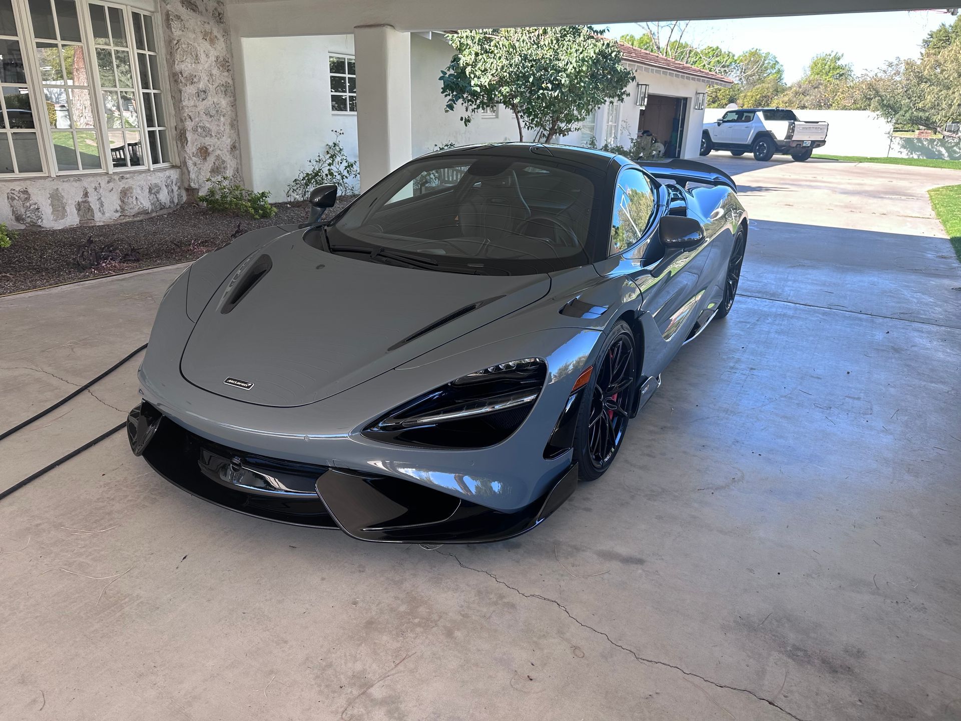 A gray sports car is parked in a driveway in front of a house.