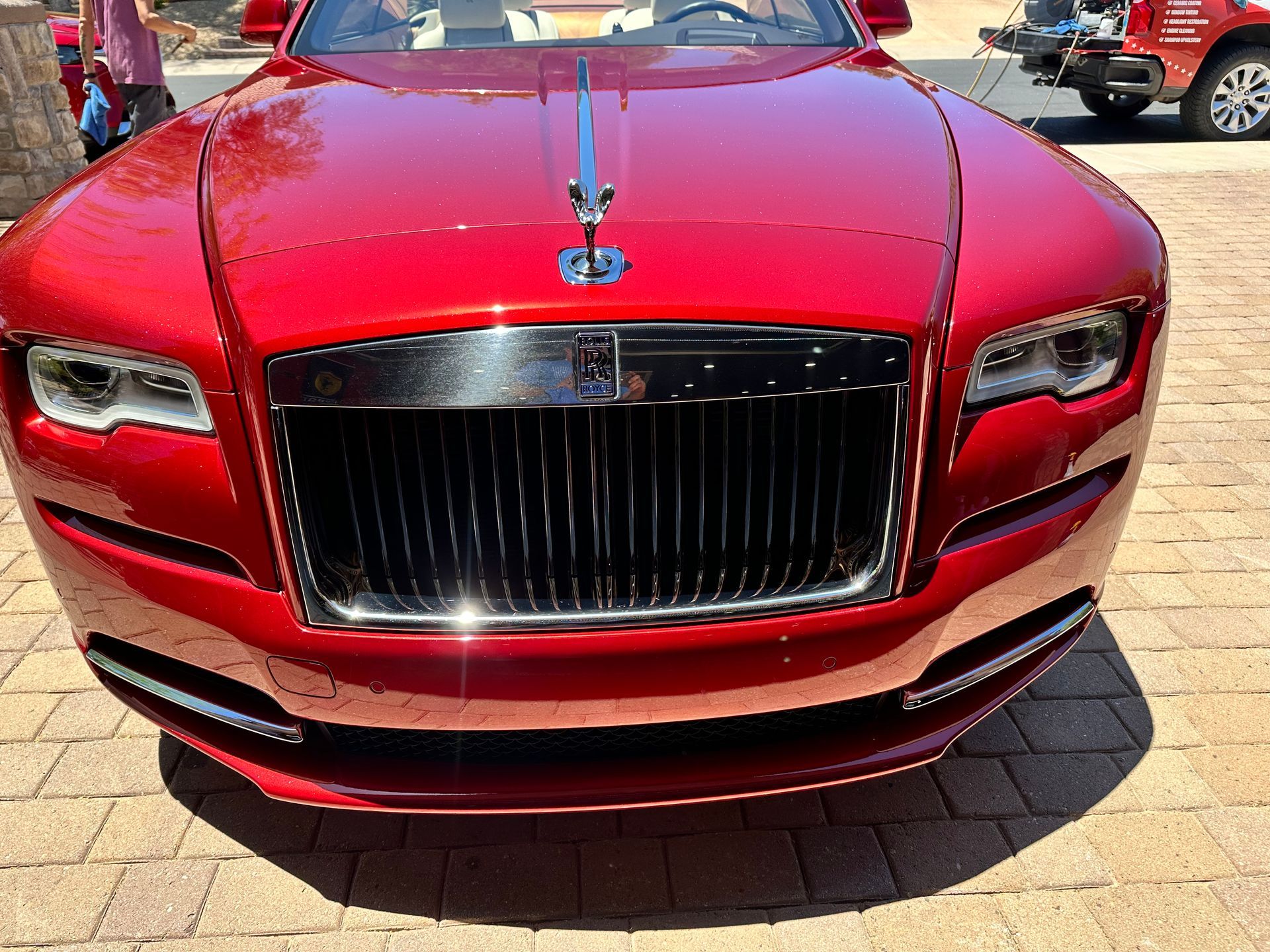 A red rolls royce is parked on a brick driveway