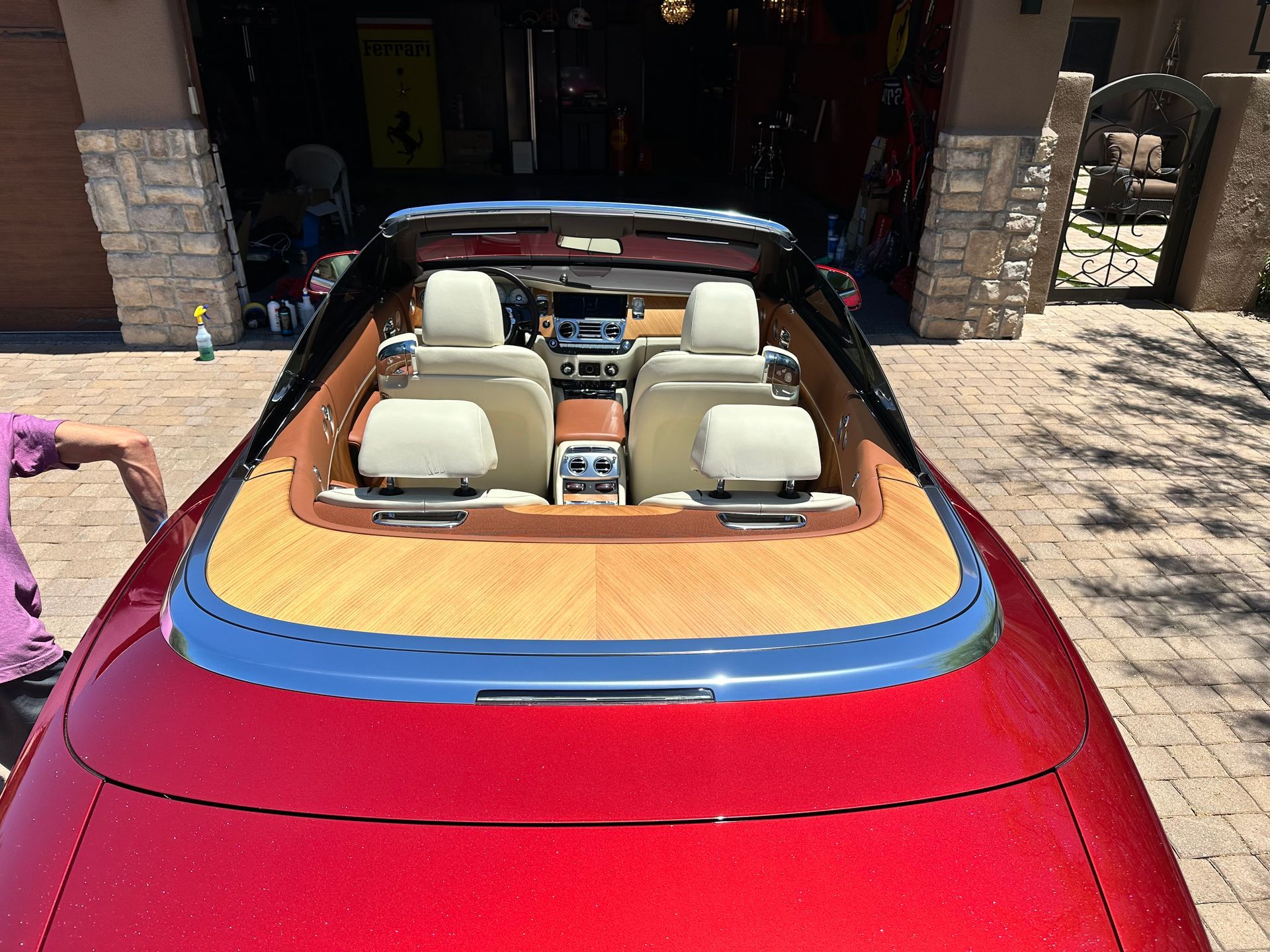 A red car with a wooden roof is parked in front of a garage.