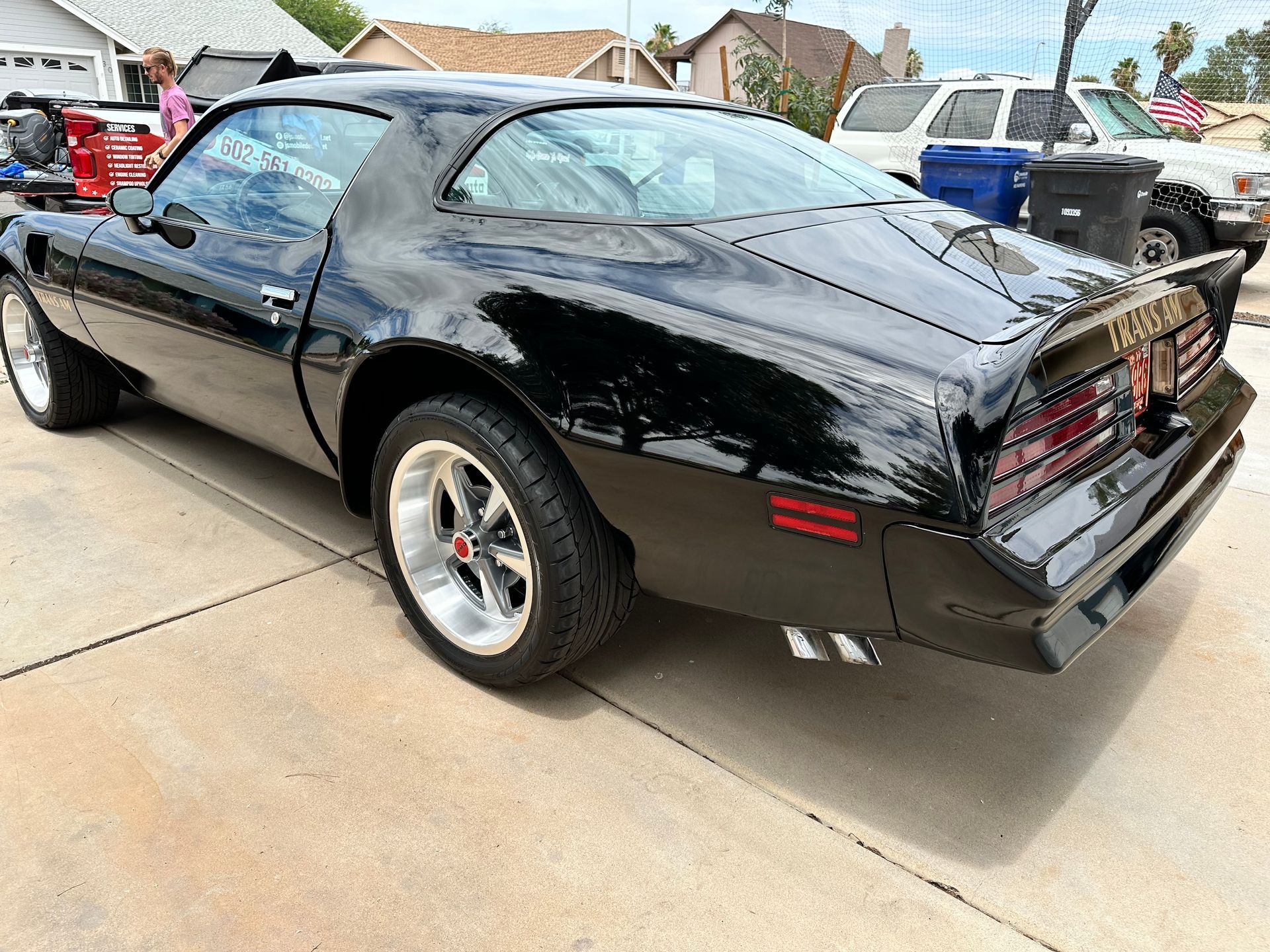 A black muscle car is parked in a driveway.