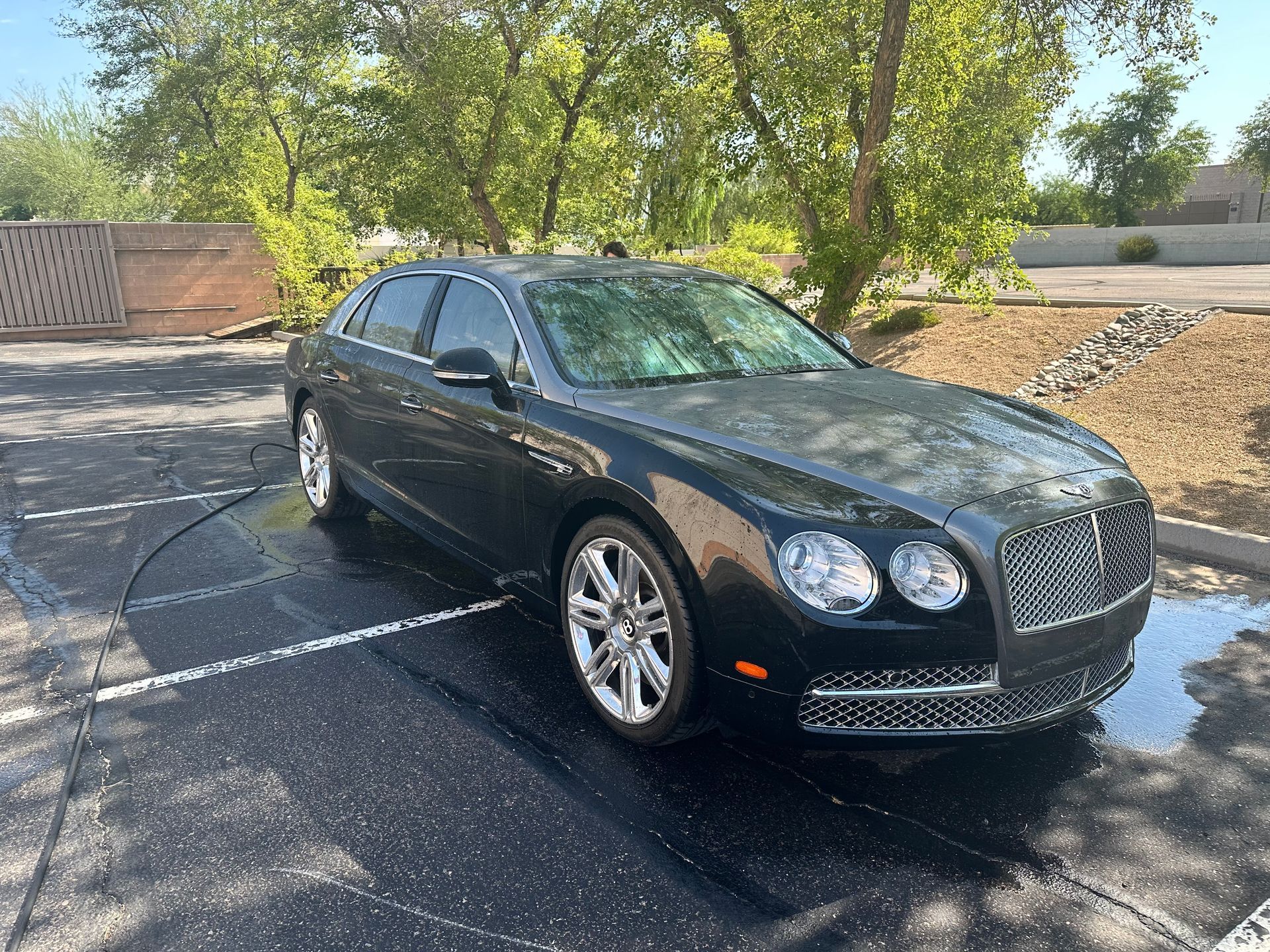 A black bentley is parked in a parking lot.