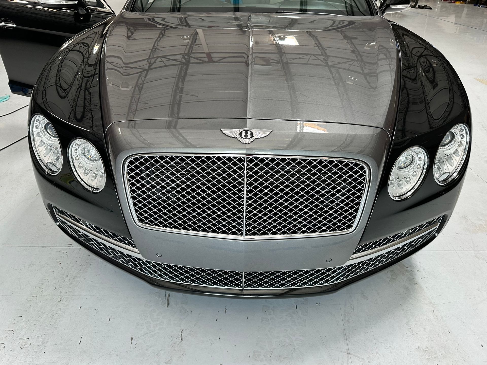 A black bentley is parked in a garage