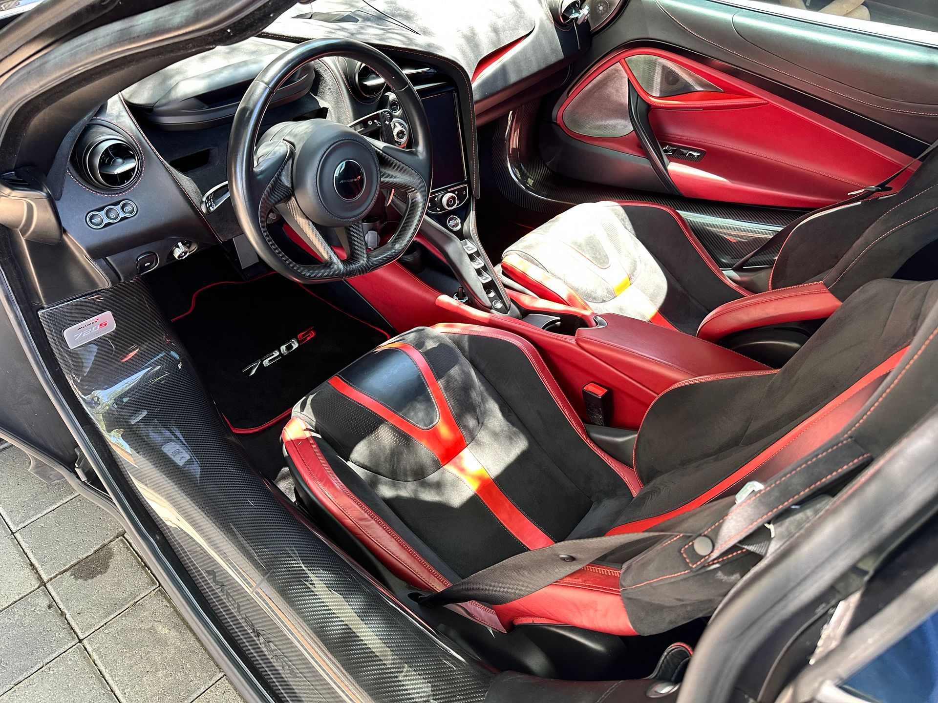 The inside of a black and red sports car with the door open.