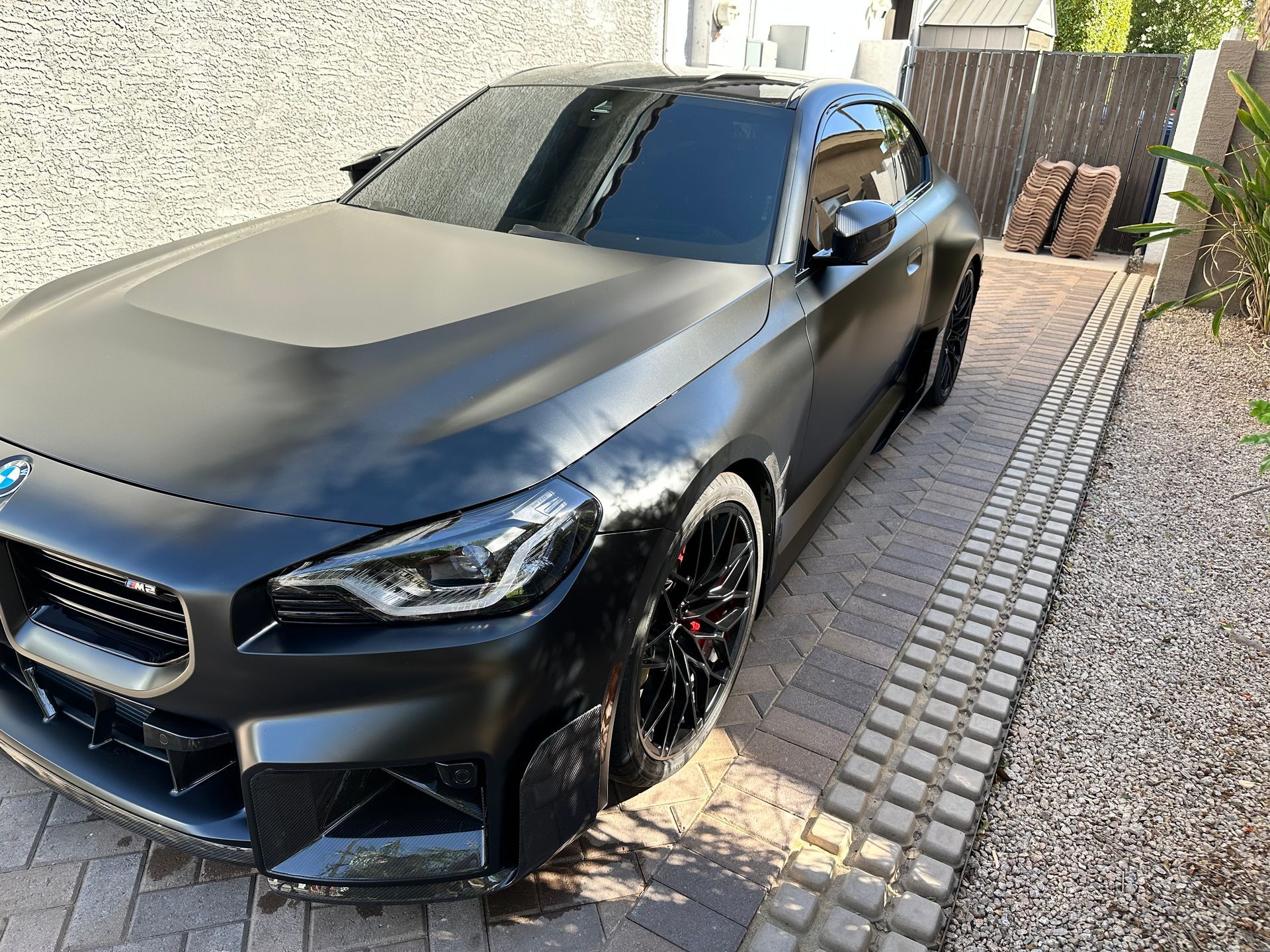A black bmw z4 is parked on a brick driveway.