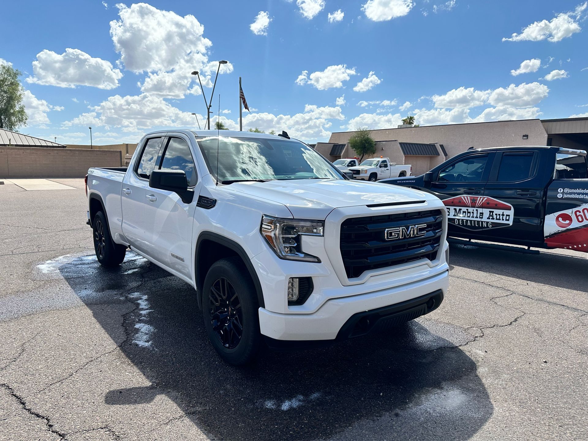 A white gmc sierra pickup truck is parked in front of a building.