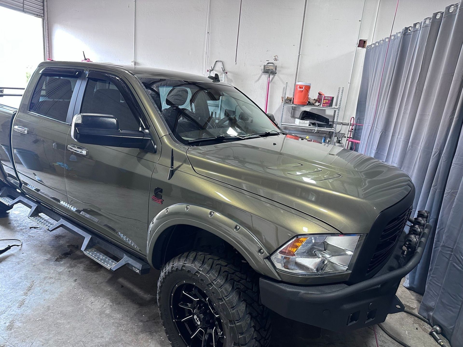 A green dodge ram truck is parked in a garage.