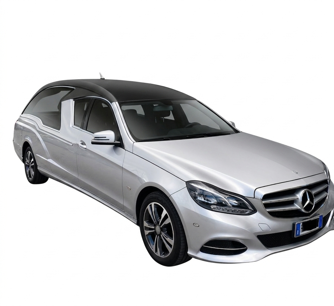 Una berlina Mercedes color argento parcheggiata fuori da una concessionaria, con un'altra auto e una gru edile sullo sfondo.