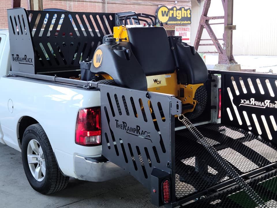 White pickup truck with a black-and-yellow lawn mower secured in a rear cargo rack