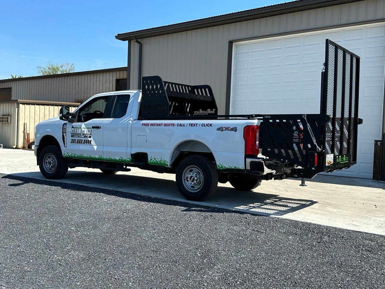 White utility truck with metal racks parked outside a warehouse building