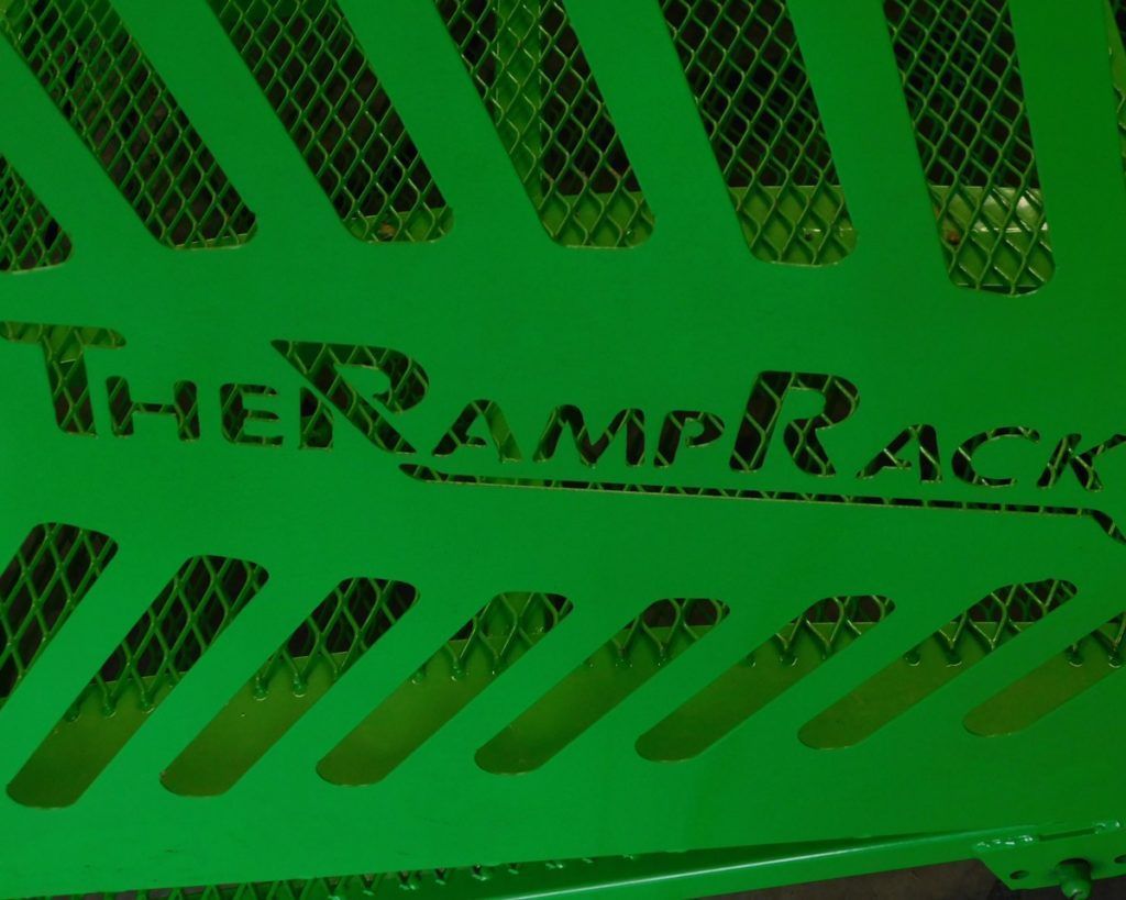 Green metal machine panel with vent slits and the text “The RampRack” painted across it