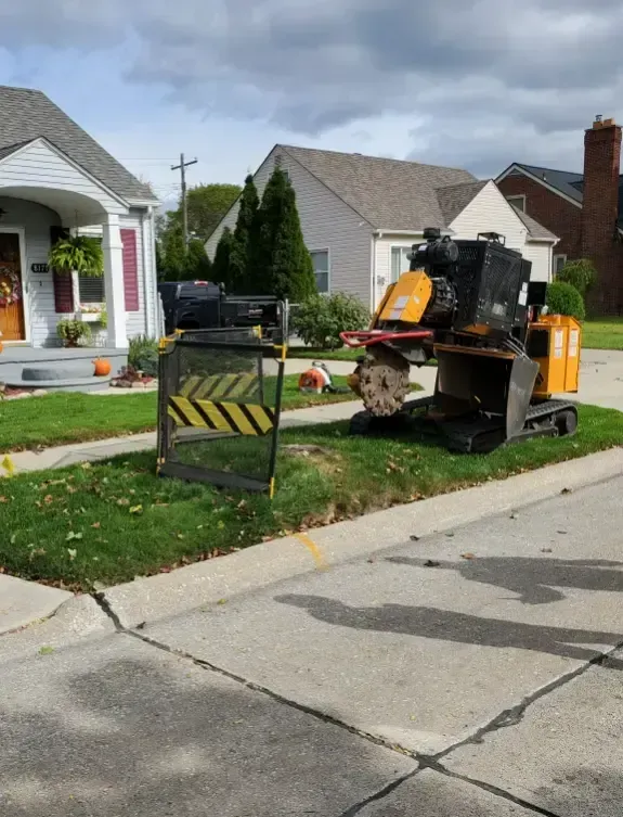 A yellow and black tractor is parked in front of a house