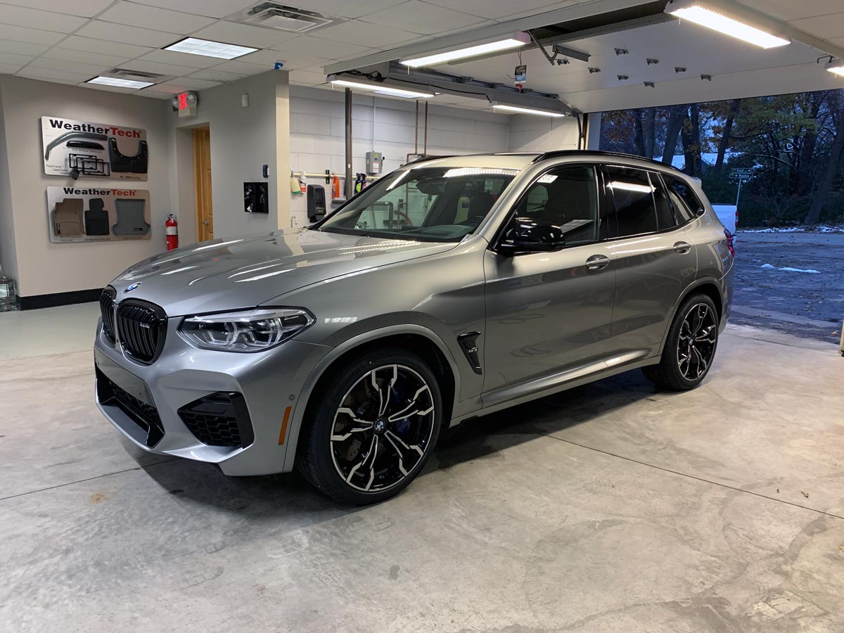 A silver bmw x3 m is parked in a garage.