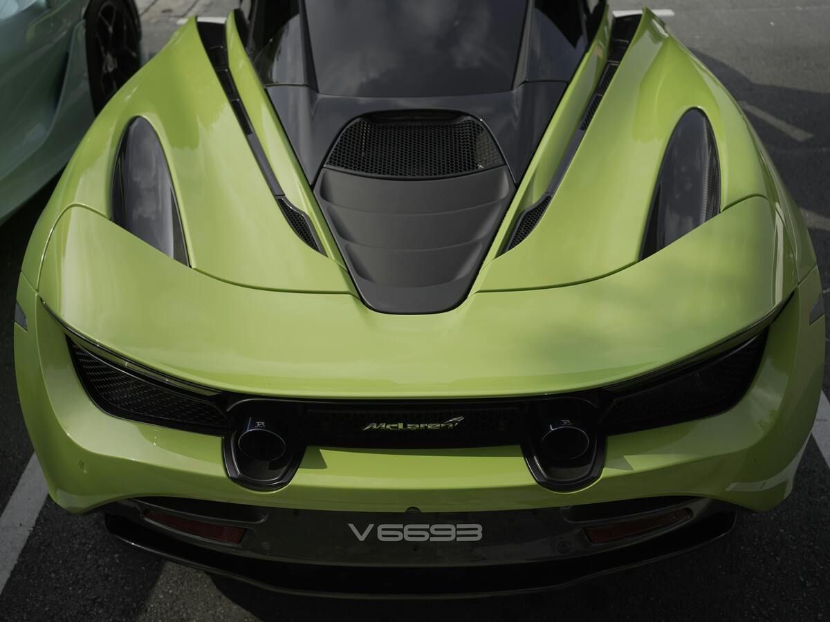 Lime green McLaren sports car rear with black accents and exhaust pipes.