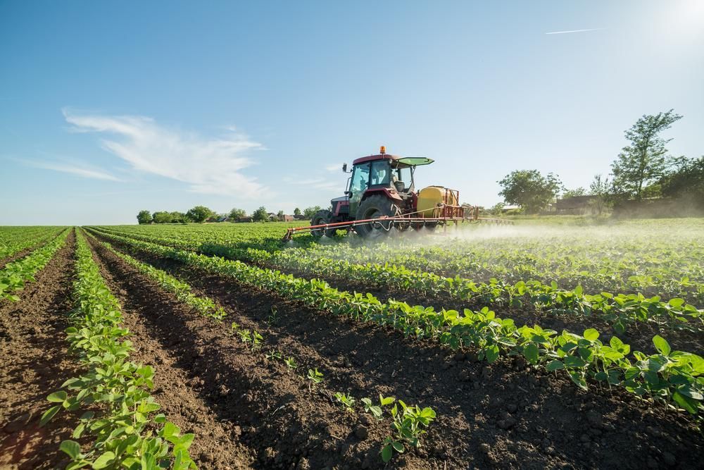 A Tractor Is Spraying Fertilizer on A Field of Plants — Kempsey Produce & Saddlery in Kempsey, NSW