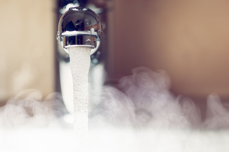 Faucet with water running and steam rising.