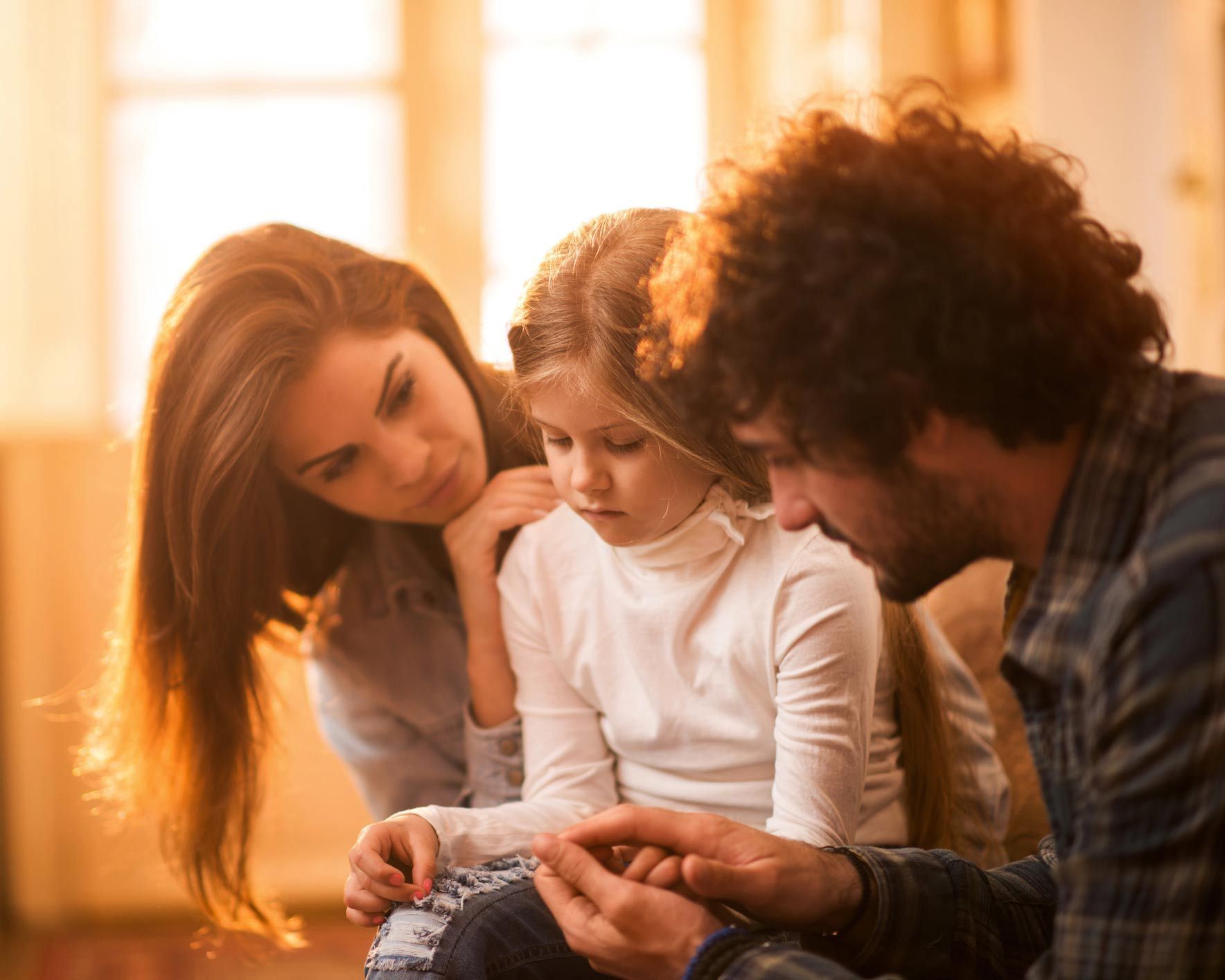 A man and woman are sitting on a couch with a little girl.