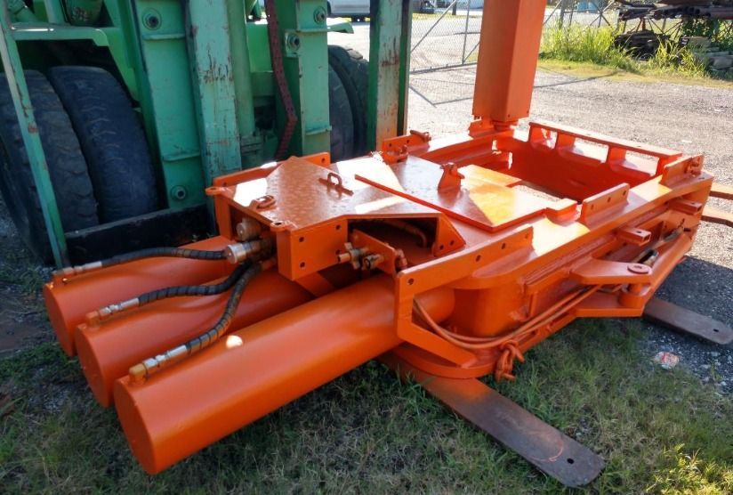 A large orange forklift is parked in the grass