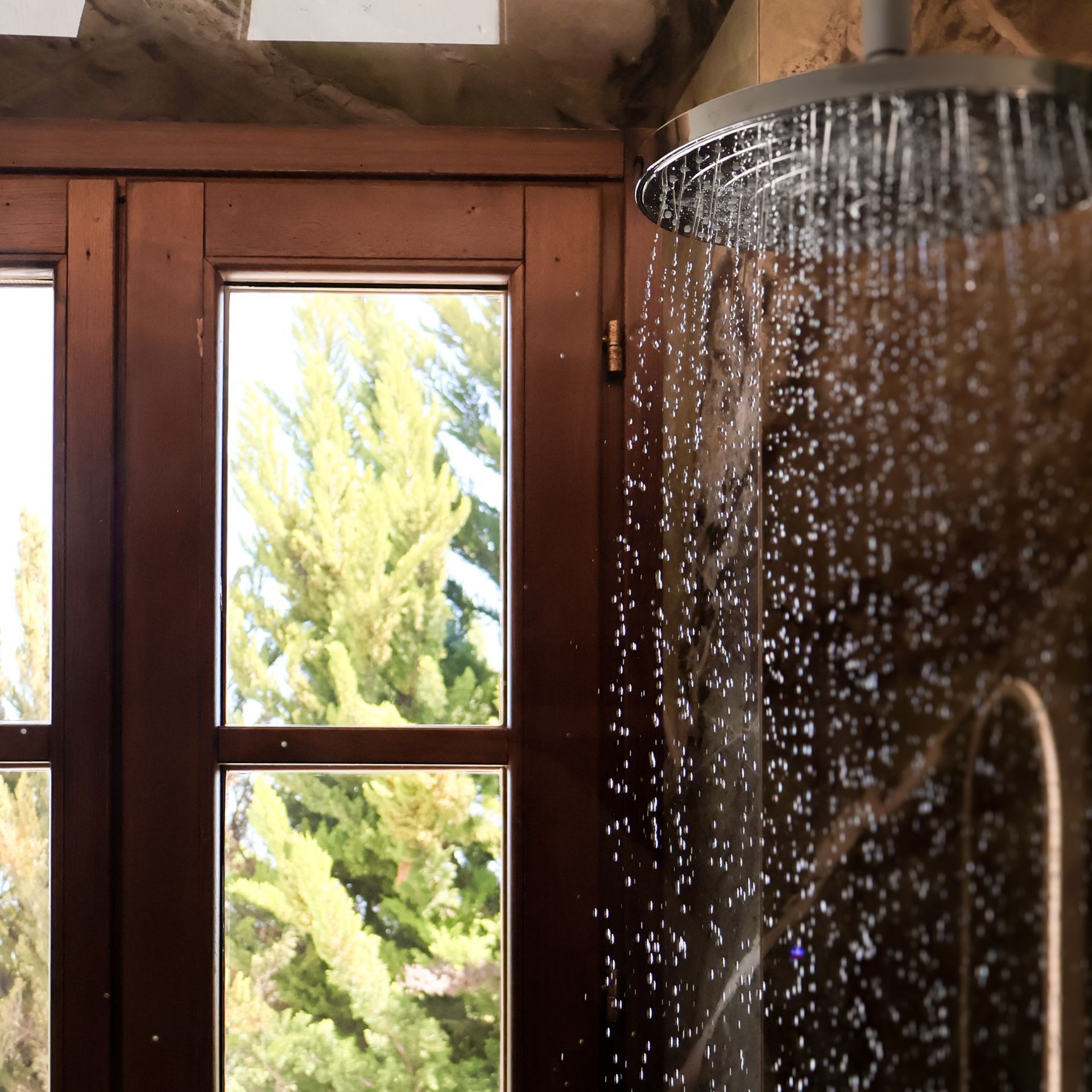 A shower head with water coming out of it in front of a window