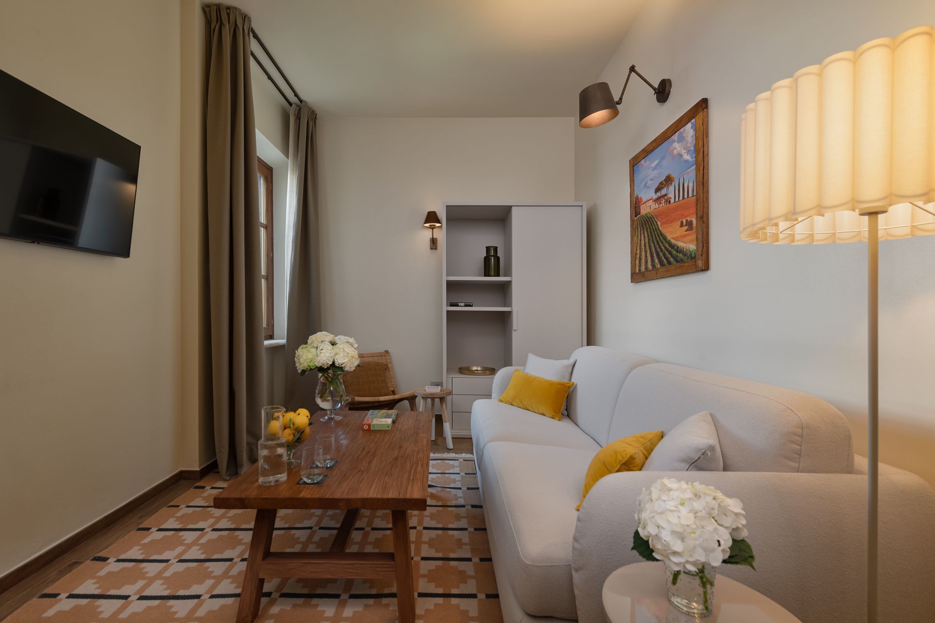 Hotel suite with a couch , chair , table and television.