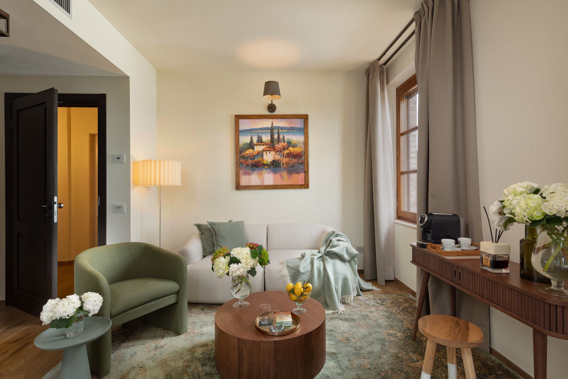 A decorated hotel suite with a couch , chair , table and a painting on the wall.