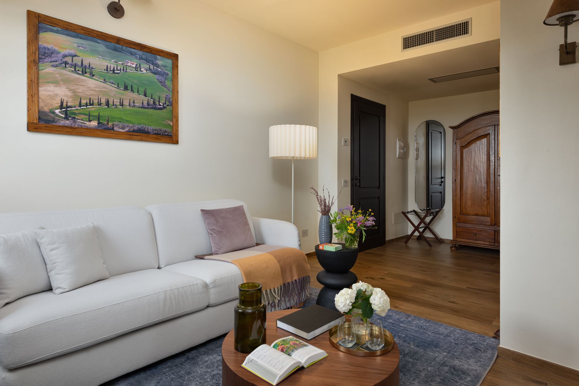 A living room with a couch , table , lamp and painting on the wall.