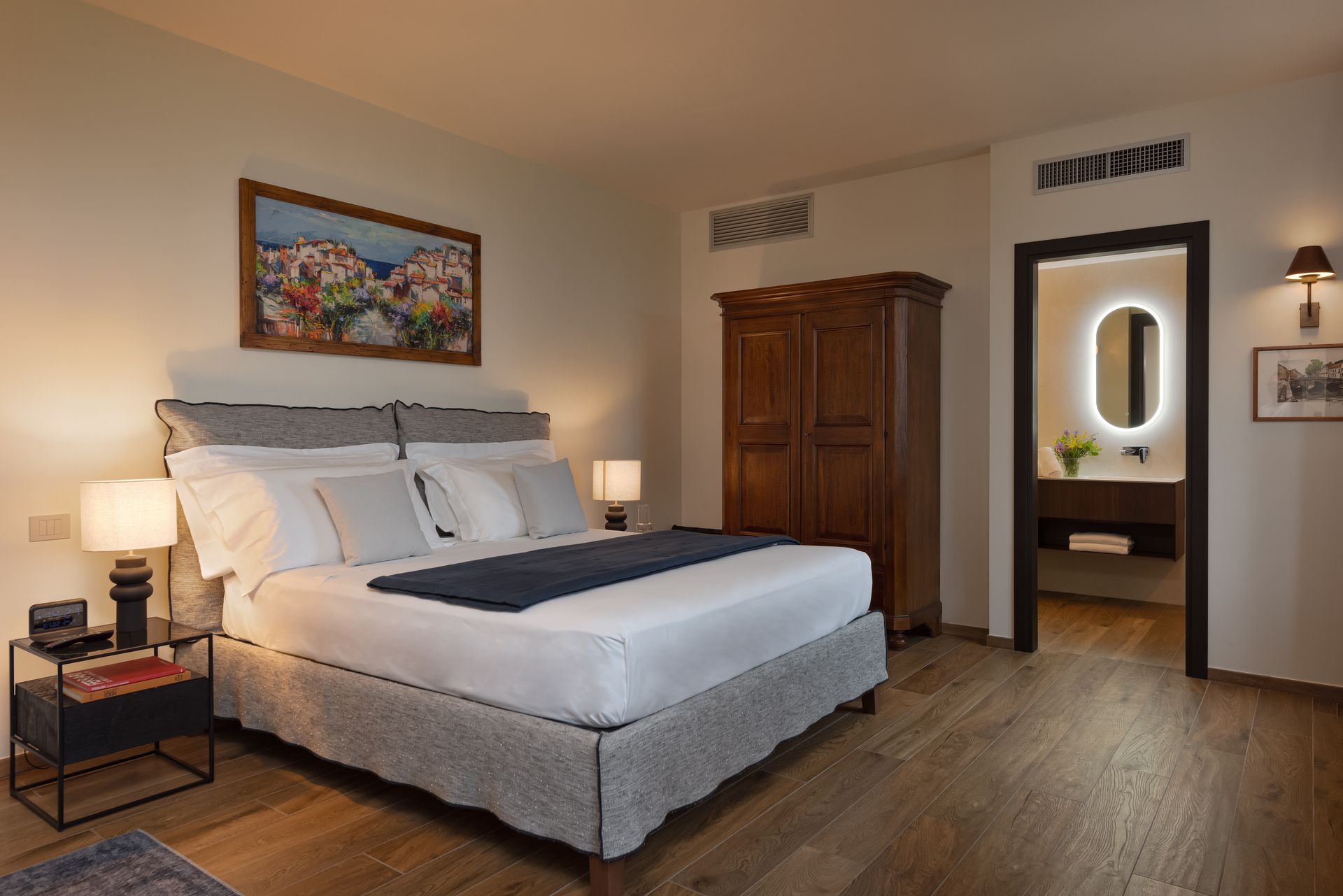 A hotel room with a king size bed , nightstands , lamps and a mirror.