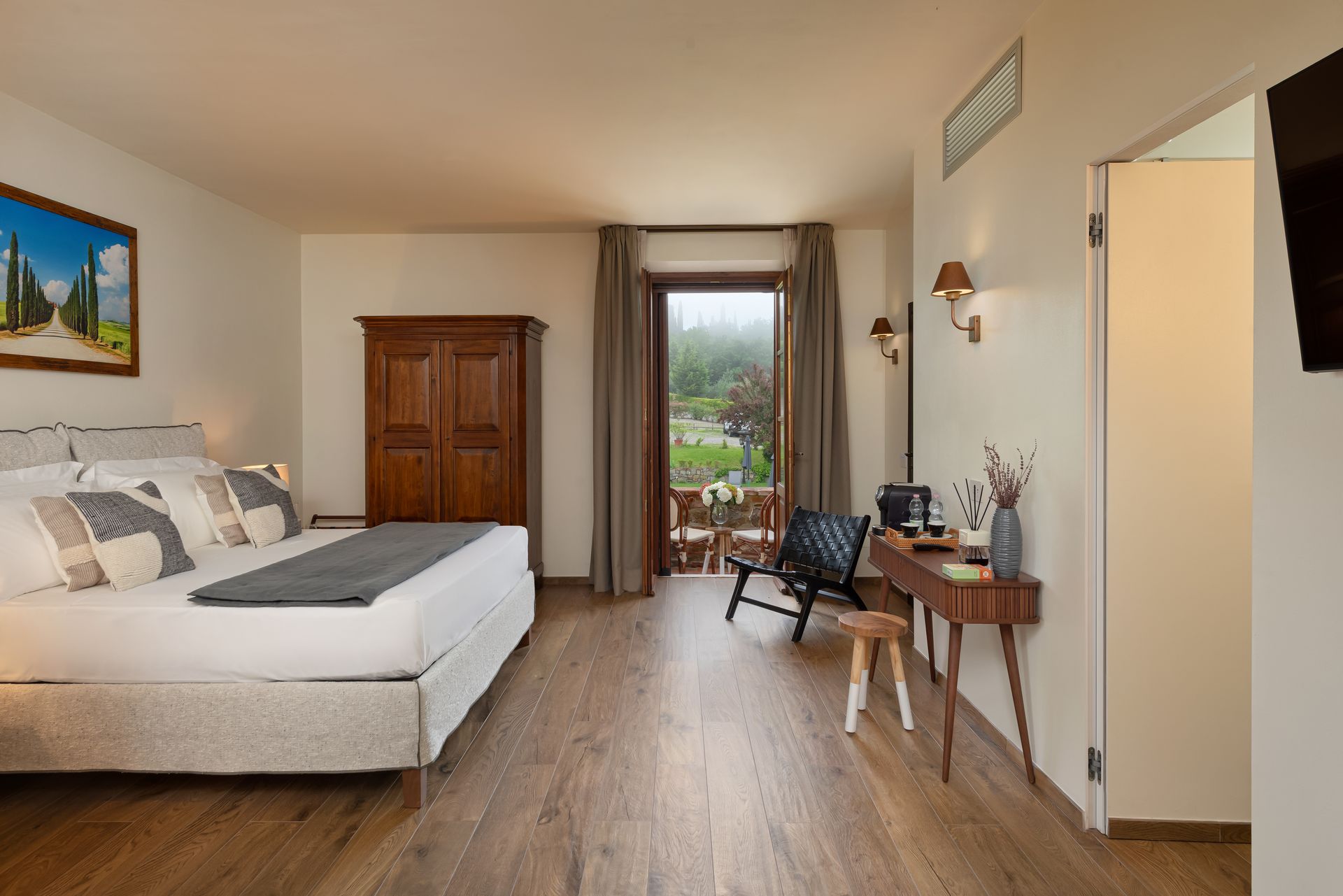 A hotel room with a king size bed , desk , chair and television near Montepulciano.