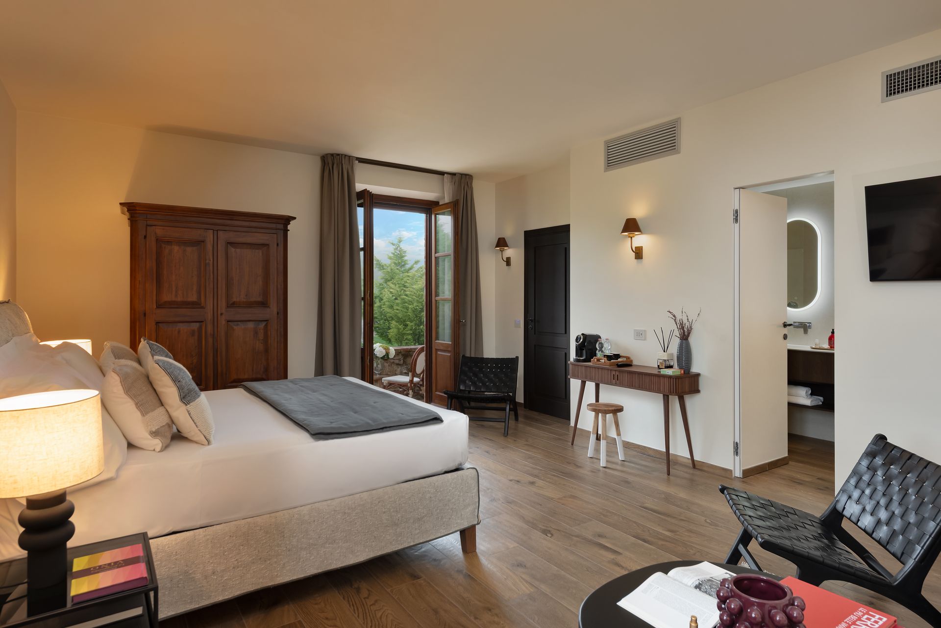 A hotel room with a king size bed , chairs , desk and television in Tuscany.