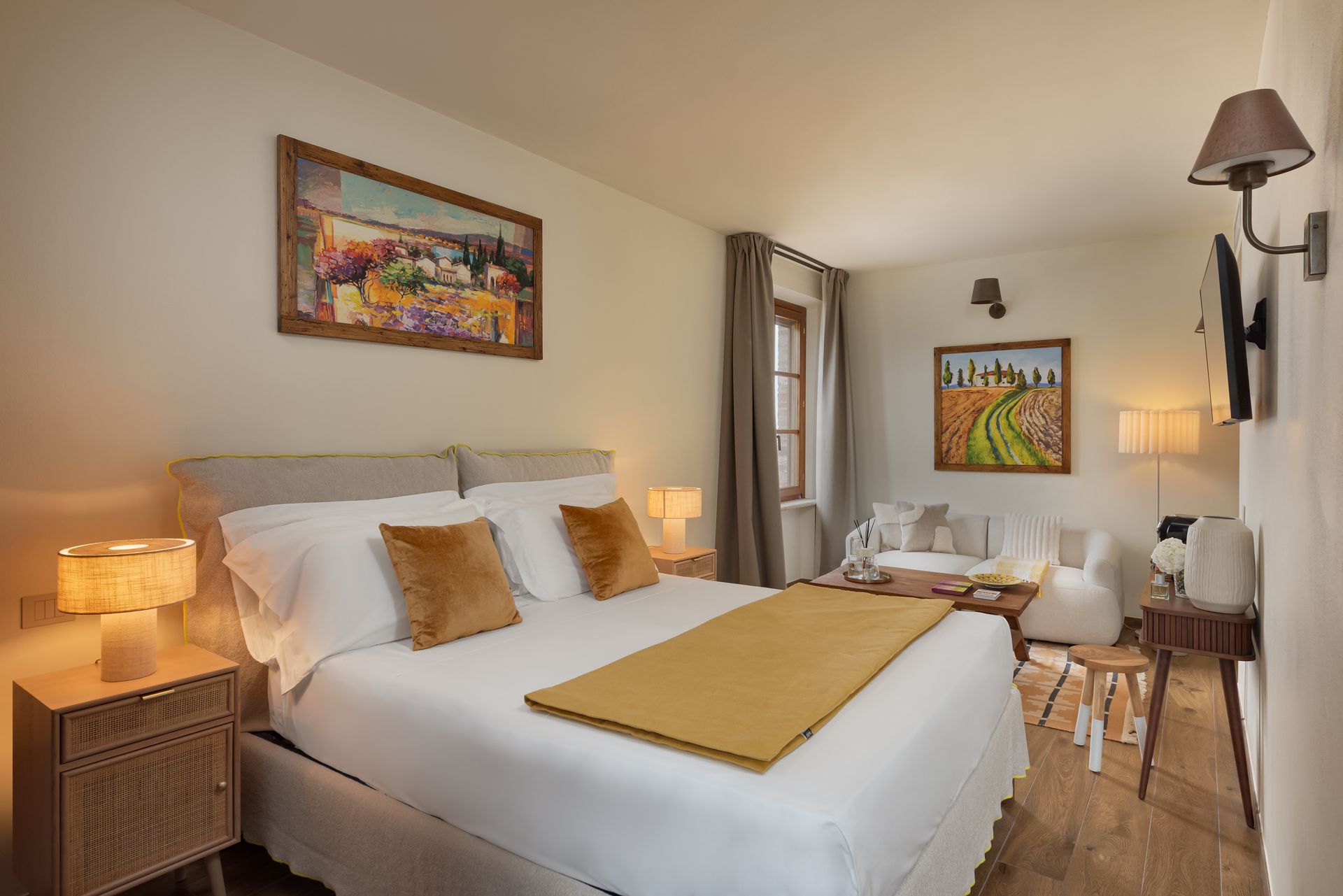 A hotel suite in Italy with a large bed , a painting on the wall , and a couch.