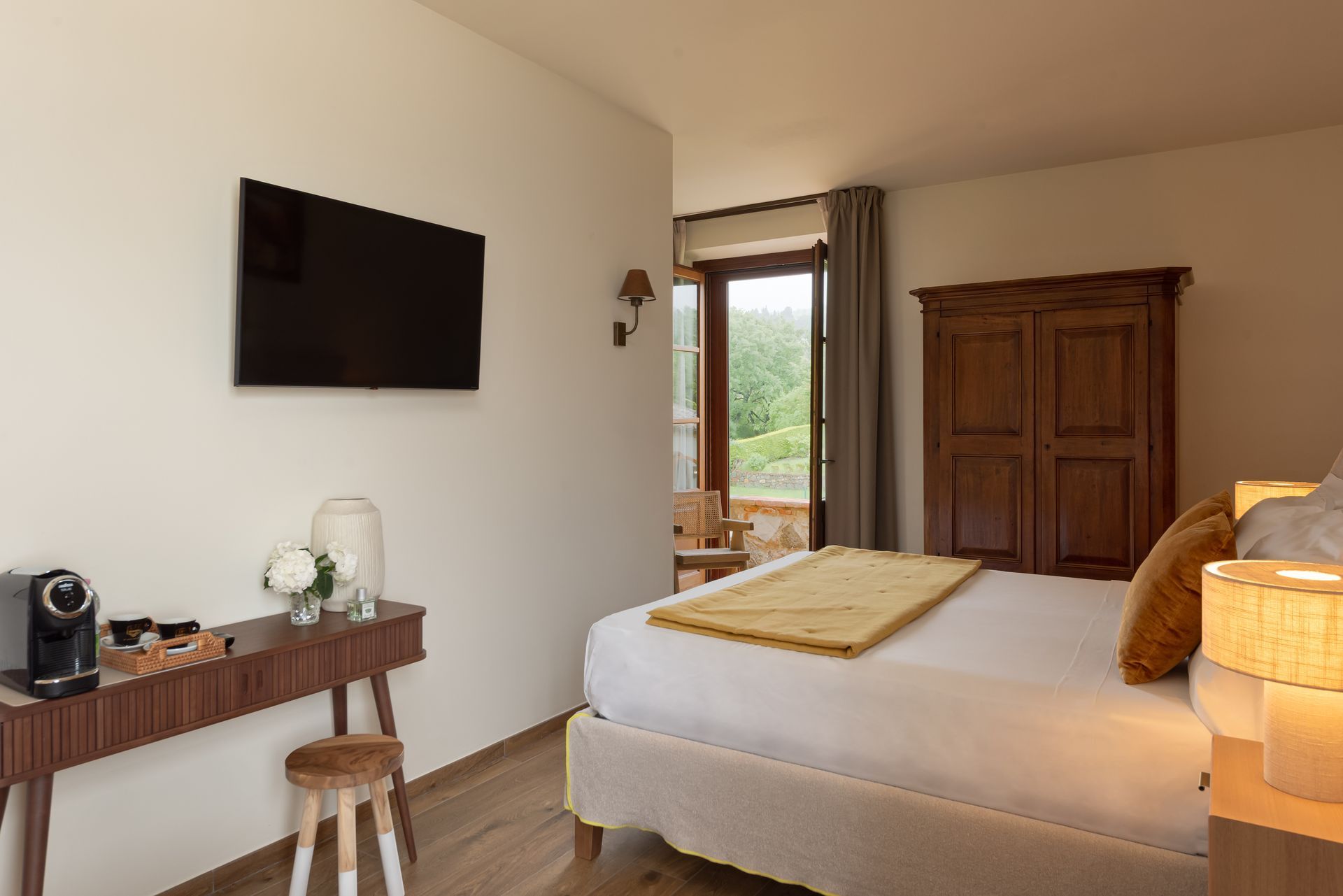 A hotel suite with a large bed and a flat screen tv on the wall and balcony.