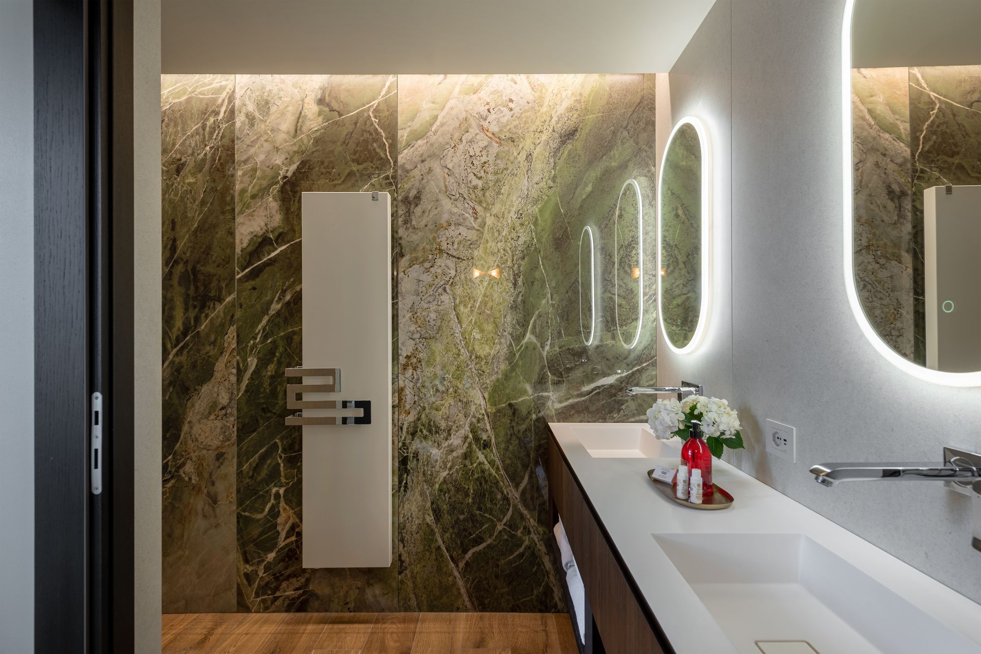 A hotel suite bathroom with a double sink , mirror and towel warmer.