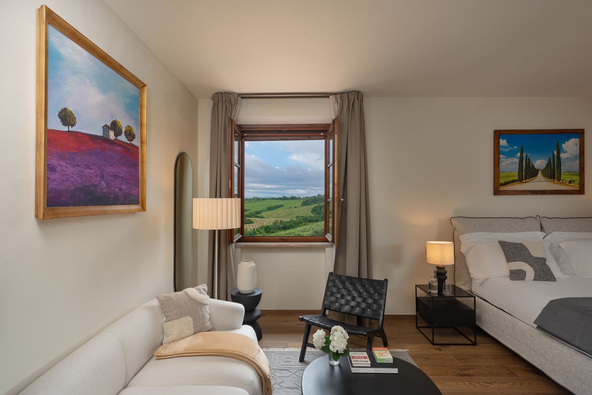 A spacious hotel suite with a couch , chair , table and a large window in Tuscany.