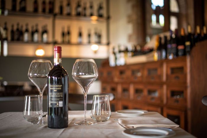 A bottle of wine is sitting on a table next to two wine glasses.