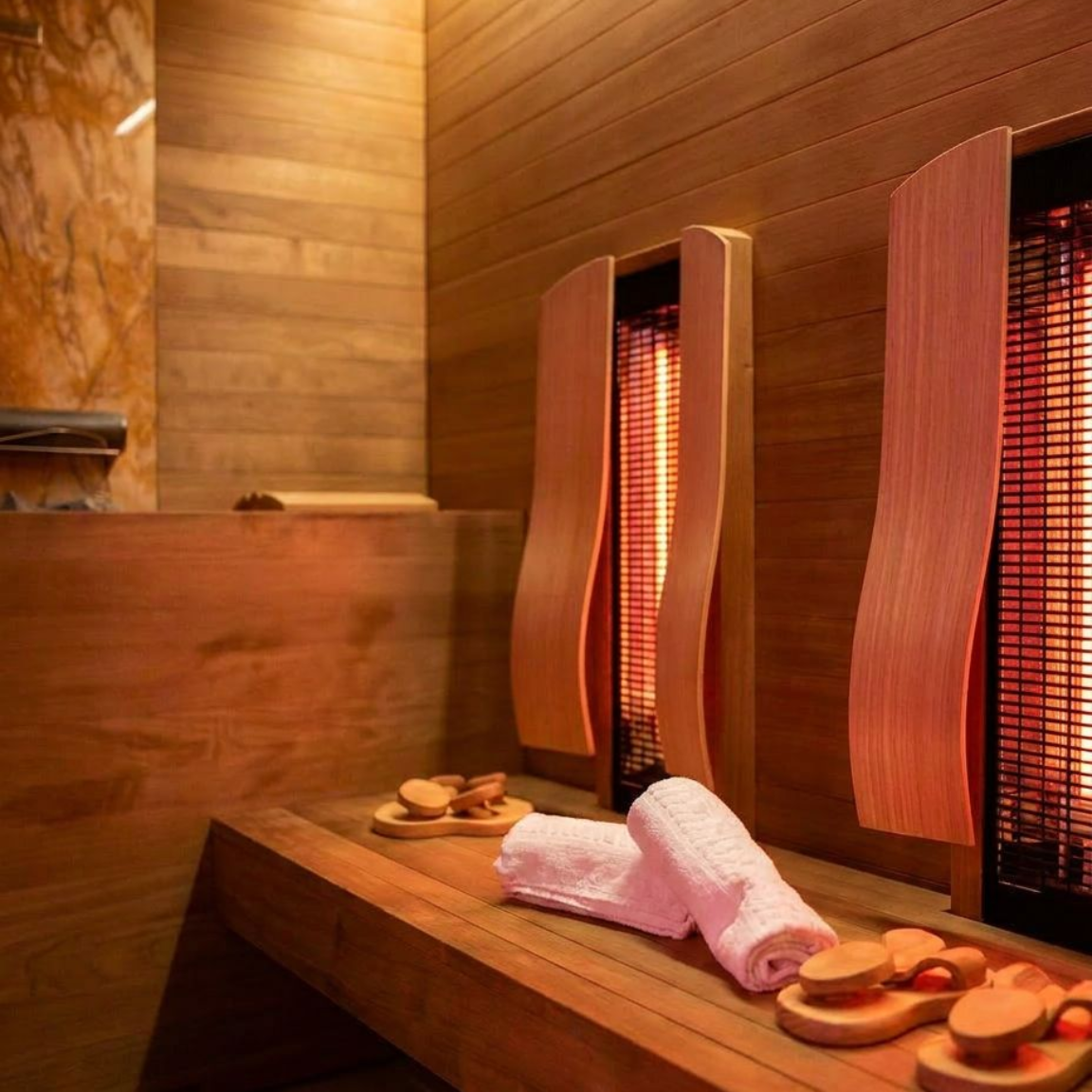 A wooden sauna with two benches and a towel on the floor.