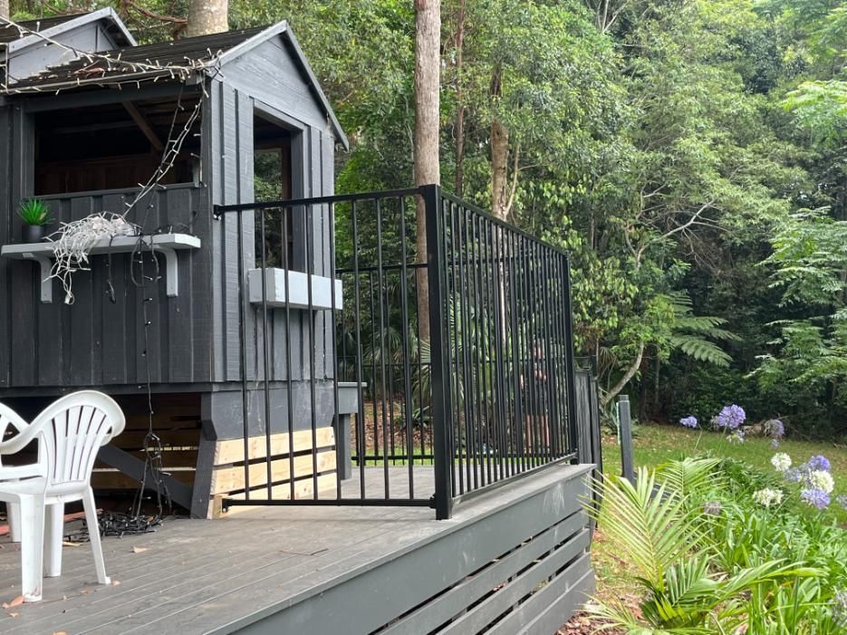 A Black Tree House With A Deck And Chairs In Front Of It — Lewis Landscapes In Yippin Creek, NSW